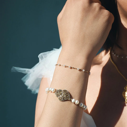 pulseira de pérolas coração de Viana da Carmo Joalheiros mostrada no pulso feminino com corrente delicada