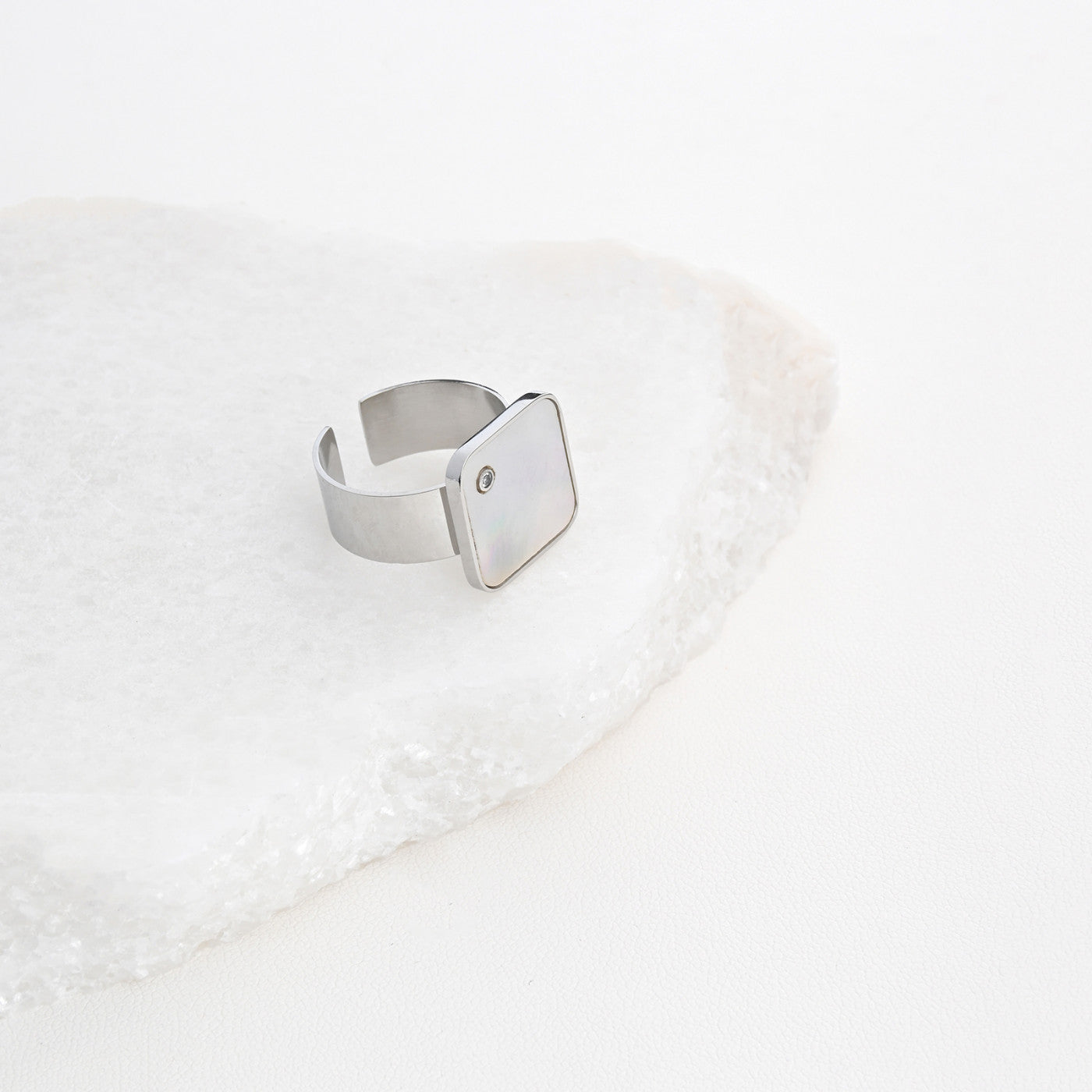 anel ajustável aço quadrado prateado com pedra discreta e design minimalista da Carmo Joalheiros sobre base de mármore branco