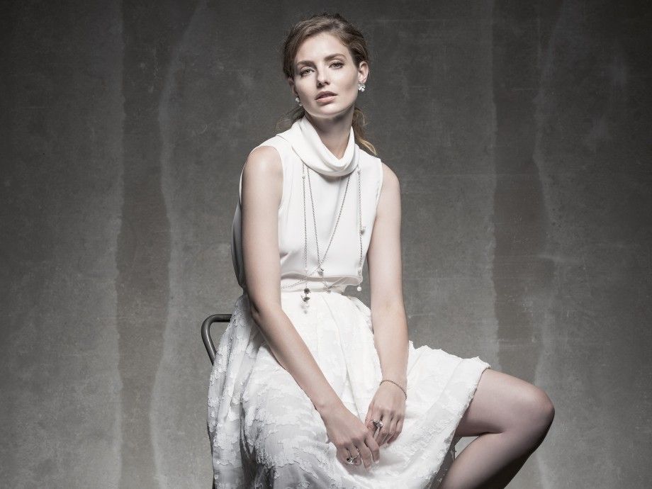 Modelo sentada com vestido branco e colar comprido feminino da Carmo Joalheiros em estudio