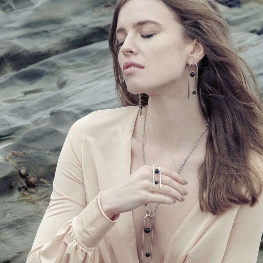 Carmo Joalheiros brinco clip moderno em prata com detalhes pretos design longo geométrico usado por mulher elegante na praia