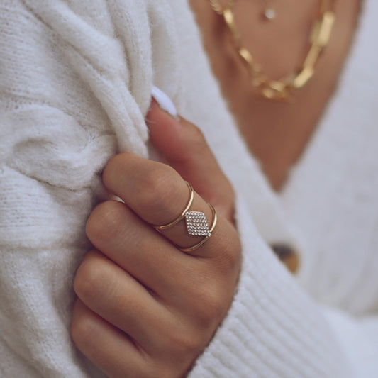 anel ajustável aço feminino dourado com pedra cravada usado em mão feminina com sueter branco Carmo Joalheiros