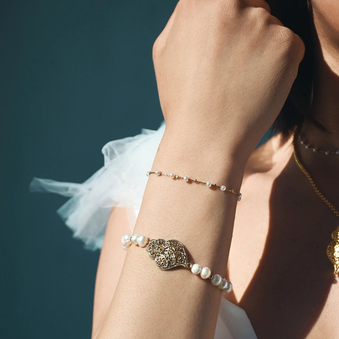 pulseira de pérolas coração de Viana da Carmo Joalheiros mostrada no pulso feminino com corrente delicada