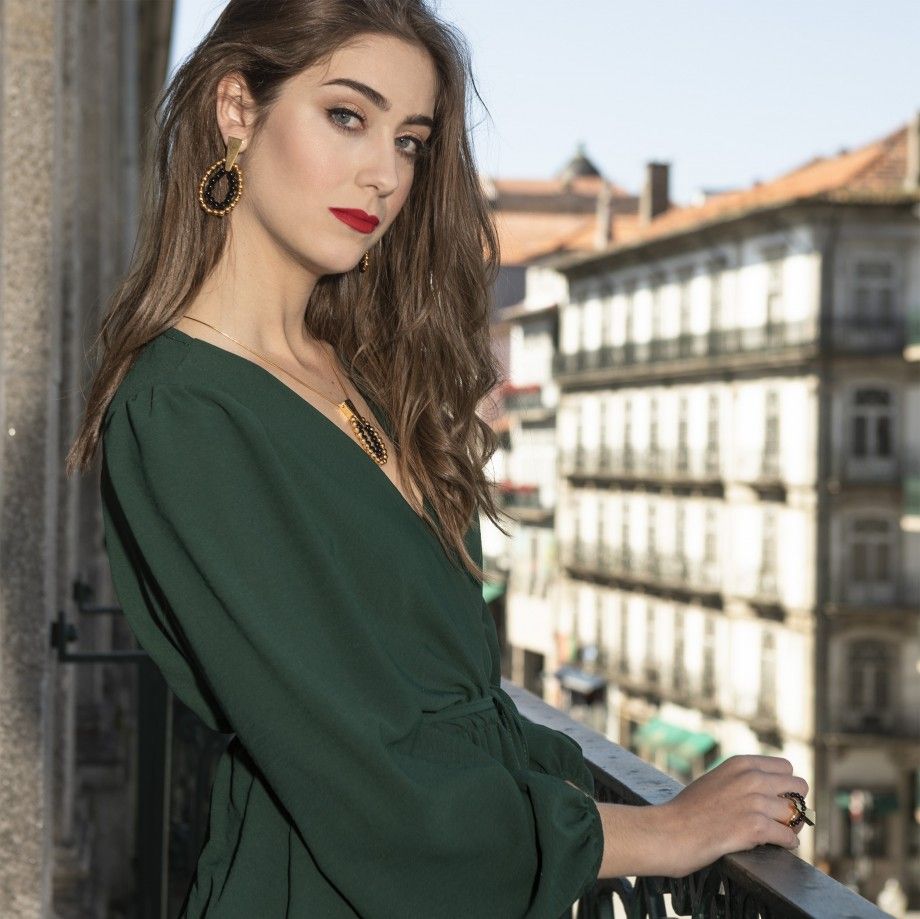 Mulher elegante numa varanda com vestido verde a usar colar pinpoint dourado da Carmo Joalheiros