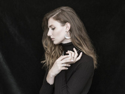 Mulher com argolas filigrana portuguesa da Carmo Joalheiros e anéis minimalistas em look elegante