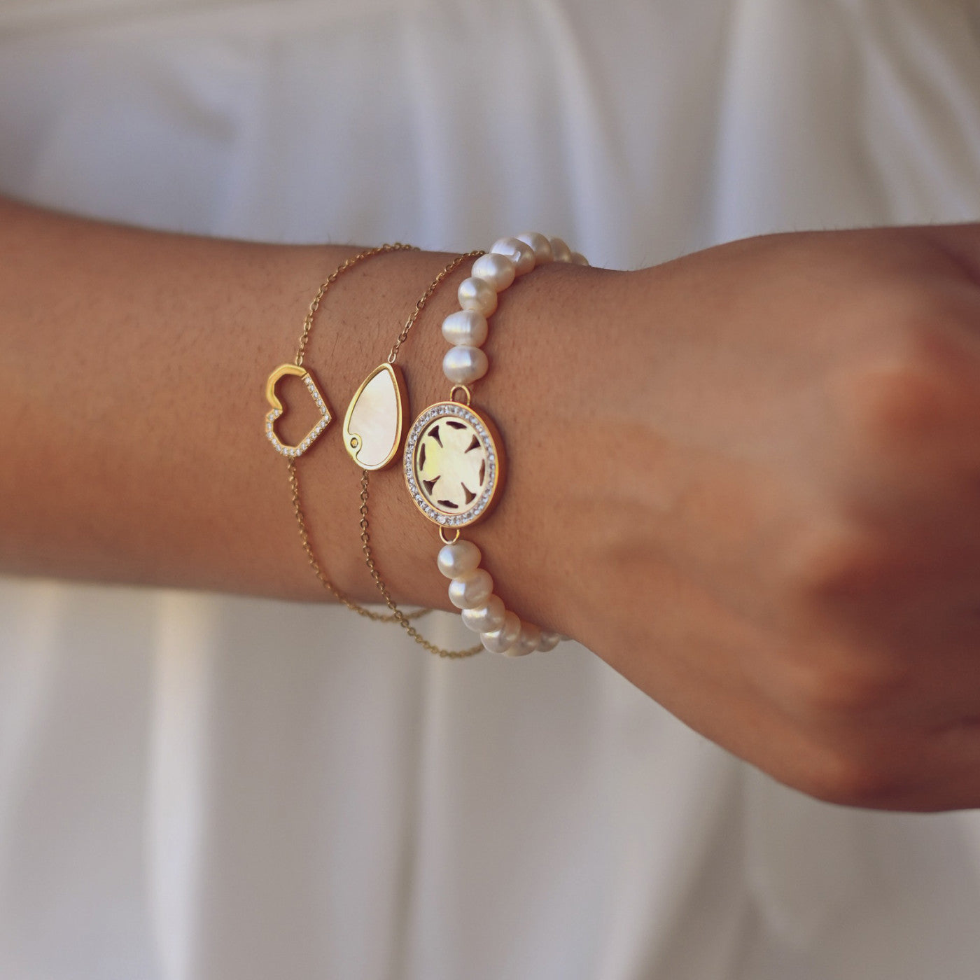 Pulso feminino com pulseira de aço com pérolas e correntes douradas finas da Carmo Joalheiros