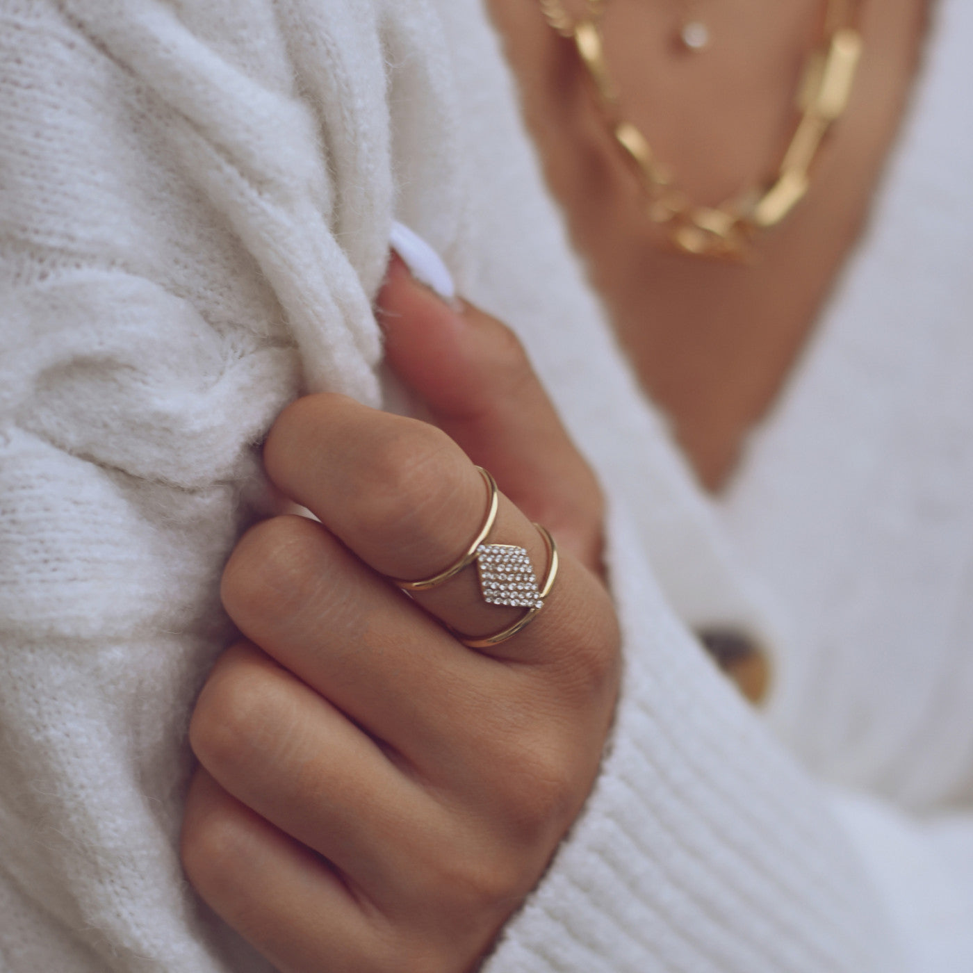 anel ajustável aço feminino dourado com pedra cravada usado em mão feminina com sueter branco Carmo Joalheiros