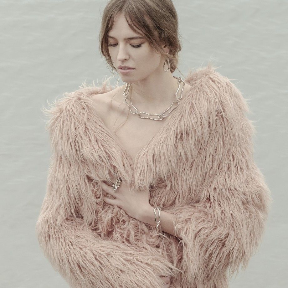 Mulher com casaco peludo e joias Topazio 1874 destacando anel broadway feminino prata e colar