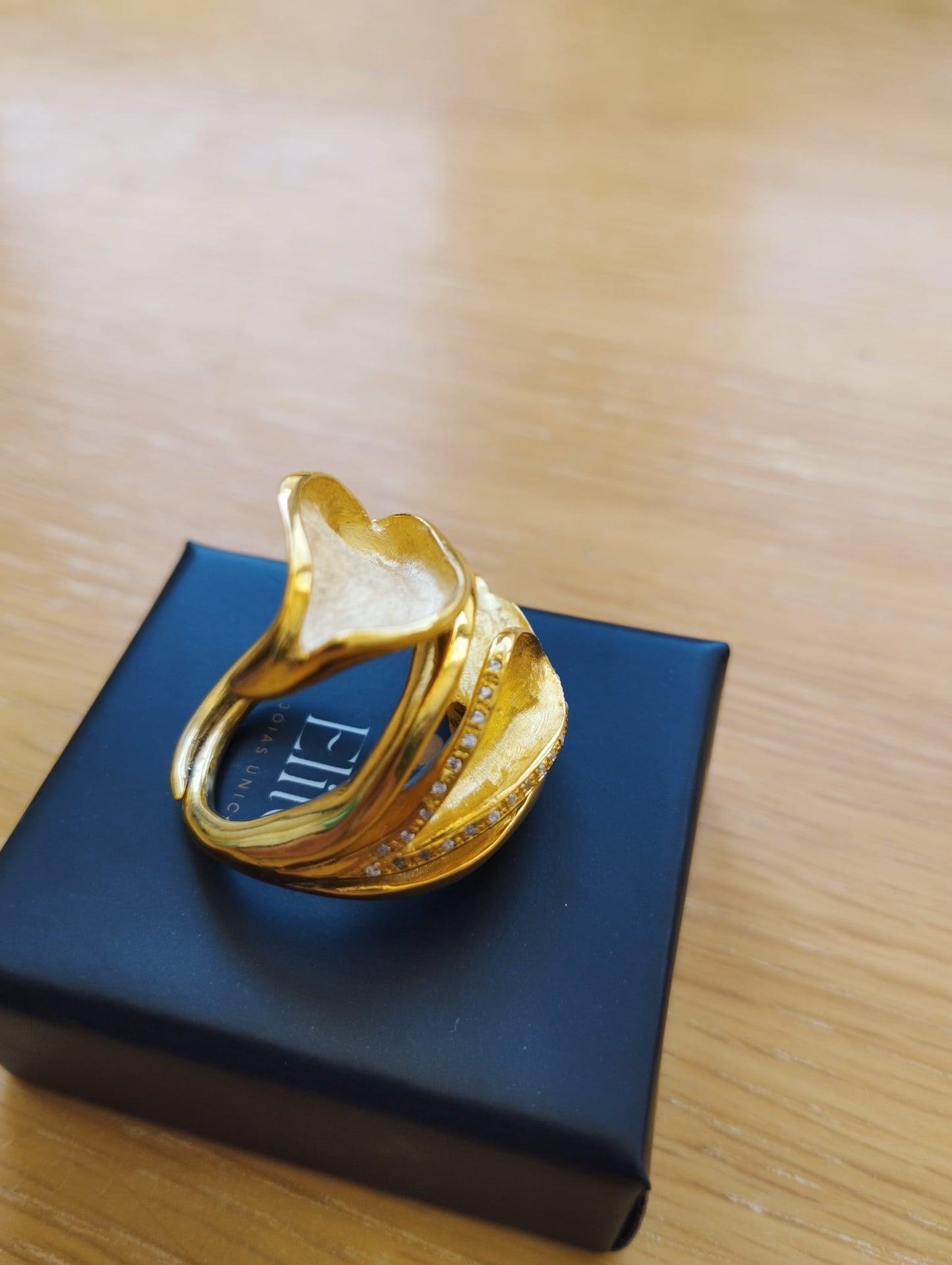 Joia Exclusiva Elite anel de ouro Lirio da Paz anel dourado com design de lirio e pedras sobre caixa preta