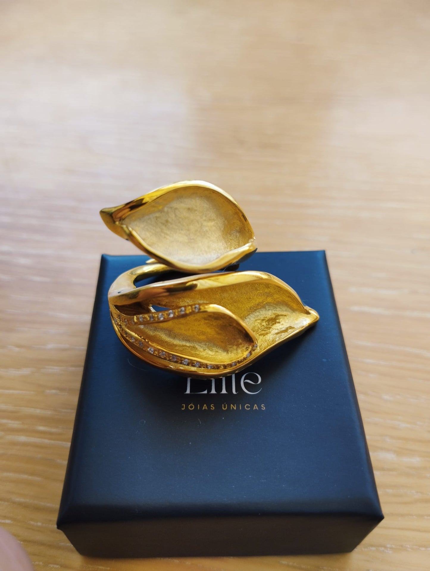 Joia Exclusiva Elite anel de ouro Lirio da Paz. Anel dourado em formato de lirio com fileiras de brilhantes sobre caixa preta