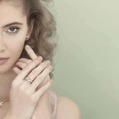 Modelo com mãos próximas ao rosto mostra anéis e brincos imagem da coleção pulseira guardian feminina Carmo Joalheiros